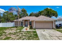 Single story home with neutral paint, arched windows, 2-car garage, and palm tree in the front yard at 13337 Tubeck St, Spring Hill, FL 34609