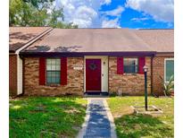 Charming brick townhouse featuring red shutters and a matching front door with a festive wreath at 35140 Whispering Oaks Blvd, Dade City, FL 33523