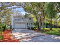 Charming two-story home with a large driveway, balcony, and mature trees at 408 Georgia Ave, Crystal Beach, FL 34681