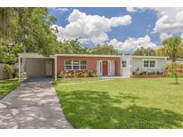 Charming single-story home with red brick accents, a spacious lawn, and mature landscaping at 505 Broxburn Ave, Temple Terrace, FL 33617