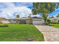 Charming single-story home with stone accents, lush lawn, and a brick driveway at 5285 Dover Ne St, St Petersburg, FL 33703