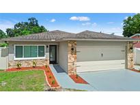 Charming single-story home featuring stone accents, a two-car garage, and a well-manicured lawn at 7021 Blossom Ave, Tampa, FL 33614