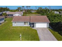 Charming single-story home with a well-manicured front lawn and attached garage at 7061 Denmark St, Englewood, FL 34224