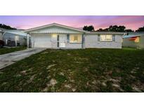 Charming single-story home featuring a well-maintained lawn and attached garage with a beautiful sunset sky at 10831 Manchester Rd, Port Richey, FL 34668