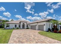 Beautiful single-story home with lush landscaping, a paver driveway, and a three-car garage at 16304 Wild Mallard Dr, Odessa, FL 33556