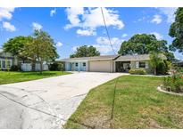 Charming single story home with a wide driveway, lush lawn, and a two-car garage at 336 Westwinds Cir, Palm Harbor, FL 34683