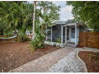 Charming single-story home featuring a screened-in porch and lush landscaping with a brick pathway to the front door at 5521 Dartmouth N Ave, St Petersburg, FL 33710