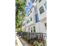 Modern townhome exterior with white facade, blue accents, black fence and lush landscaping at 6605 N Nebraska Ave # 23, Tampa, FL 33604