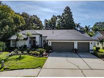 Stunning single-story home featuring a three-car garage, beautiful landscaping, and a charming front yard at 910 Kingscote Ct, Safety Harbor, FL 34695