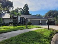 Charming home with well-kept lawn, three-car garage, and tasteful landscaping under a partly cloudy sky at 910 Kingscote Ct, Safety Harbor, FL 34695