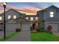 Charming townhome exterior featuring a well-maintained lawn and attached garage at 9907 Carlsdale Dr, Riverview, FL 33578