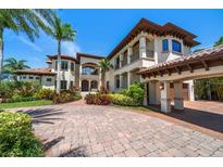 Elegant Mediterranean-style home showcasing a porte-cochere, lush landscaping, and a brick circular driveway at 10930 Spring St, Largo, FL 33774