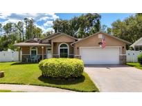 Charming single Gathering home with an attached two car garage, manicured lawn, and American flag at 11362 Heritage Way, Largo, FL 33778