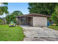 Exterior view of a home with a covered parking area and front yard at 1213 Cuttingin Pl, Tampa, FL 33612