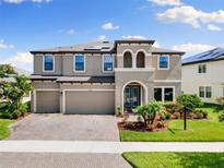 Stunning two-story home featuring a three-car garage and beautifully landscaped front yard at 12821 Satin Lily Dr, Riverview, FL 33579