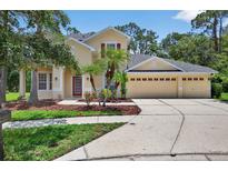 Charming two-story home with a three car garage, palm trees, and manicured lawn at 16102 Colchester Palms Dr, Tampa, FL 33647