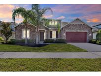 Beautiful single-story home featuring stone accents, a manicured lawn, and a two-car garage at 2120 Gwynhurst Blvd, Wesley Chapel, FL 33543