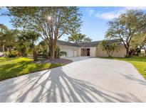 Charming single-story home featuring a circular driveway, mature trees, and a well-manicured lawn at 4157 Marine Pkwy, New Port Richey, FL 34652