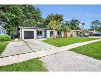Charming single-story home featuring a modern exterior, landscaped yard, and a driveway leading to an attached garage at 4441 16Th N St, St Petersburg, FL 33703