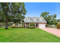 Charming one-story brick home featuring a large front yard with mature trees and manicured landscaping at 4611 W 18Th Ave, Bradenton, FL 34209