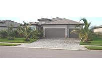 Beautiful single-story home featuring a well-maintained lawn, tropical landscaping, and a three-car garage with a paver driveway at 4957 Seafoam Trl, Bradenton, FL 34211