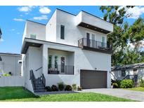 Contemporary home with clean lines, multi-level balconies, an attached garage, and lush landscaping at 5006 W Idaho St, Tampa, FL 33616