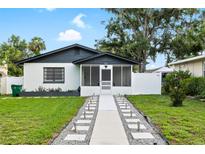Charming single-story home boasts a screened-in porch, manicured lawn, and inviting walkway at 5055 9Th St, Zephyrhills, FL 33542