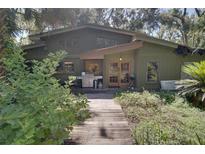 A charming exterior view showcases a unique home design with a wood pathway and lush landscaping at 6924 Valrie Ln, Riverview, FL 33569