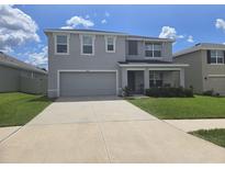Charming two-story home features a two-car garage, well-maintained lawn, and inviting front porch at 7575 Sail Clover Ln, Zephyrhills, FL 33540
