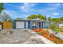 Charming blue single-story home with a well-manicured lawn, complemented by a red front door and attached garage at 8033 Norwich Dr, Port Richey, FL 34668