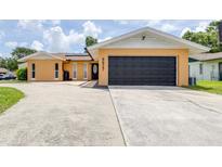 Charming single-story home featuring a large driveway and black garage door, with a well-maintained lawn at 8927 95Th N St, Seminole, FL 33777
