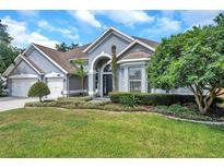 Beautifully landscaped front yard with lush green lawn and mature trees enhances this home's curb appeal at 9202 Brindlewood Dr, Odessa, FL 33556