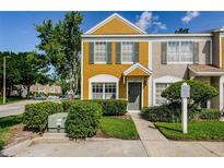 Charming two-story townhome featuring a yellow facade, green shutters, and well-maintained landscaping at 1241 Redondo Way, Wesley Chapel, FL 33543