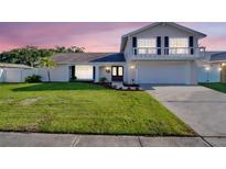 Charming two-story home features a well-manicured lawn, a balcony, and an attached two-car garage at 2897 Rosery Ne Rd, Largo, FL 33771
