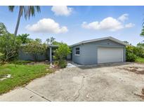 Single-story home with a gray exterior, an attached garage and a large concrete driveway at 4101 Shore Acres Ne Blvd, St Petersburg, FL 33703