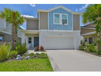 Charming two-story home with a well-manicured lawn, palm trees, and a two-car garage at 5438 Summer Sunset Dr, Apollo Beach, FL 33572