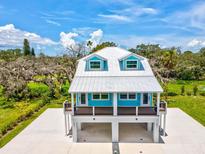 Charming coastal-style home with a metal roof, eye-catching blue accents and a raised design with covered parking at 6679 Wander Ln, New Port Richey, FL 34652