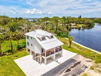 Stunning elevated home featuring a metal roof, pink accents, and a lovely balcony overlooking the serene waterfront at 6707 Wander Ln, New Port Richey, FL 34654