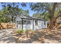 Charming single-story home with white siding and black trim, nestled among mature trees at 6806 N 17Th St, Tampa, FL 33610