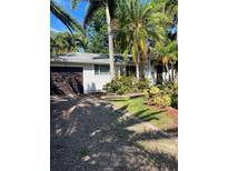 Charming home featuring a one-car garage, well-maintained lawn, and tropical landscaping at 715 Riverside Dr, Tarpon Springs, FL 34689
