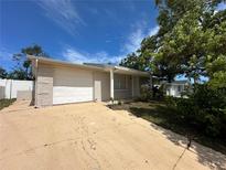 Charming one-story home featuring an attached garage and well-maintained front yard with mature trees at 9411 Rainbow Ln, Port Richey, FL 34668