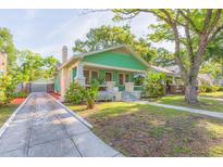 Charming green bungalow with a welcoming front porch and a well-manicured lawn and a detached garage at 1202 E Mohawk Ave, Tampa, FL 33604