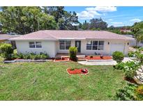 Charming single-story home featuring a well-maintained lawn and colorful, landscaped flowerbeds at 1223 Jasmine Way, Clearwater, FL 33756