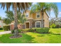 Two-story home featuring stone accents, well-maintained landscaping, and palm trees at 13830 Trull Way, Hudson, FL 34669