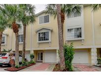 Two-story townhome exterior with palm trees, brick pavers, and white garage doors at 163 Brent Cir, Oldsmar, FL 34677