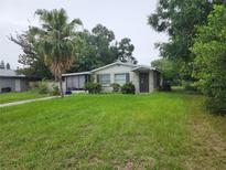 Charming single-story home featuring a cozy front porch, mature trees, and a spacious lawn at 1711 E Poinsettia Ave, Tampa, FL 33612