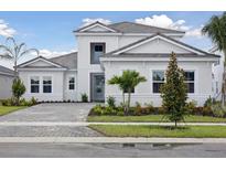 Beautiful two-story home with modern architecture, manicured landscaping and a brick paver driveway at 17555 Glistening Ct, Venice, FL 34293