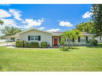Charming home featuring a well-manicured lawn, a bright red front door, and lovely landscaping at 1857 N Belleair N Rd, Clearwater, FL 33764
