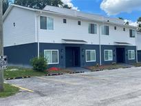 View of a two-story townhome building with designated parking spaces and landscaped entryways at 1935 Oxnard Ct, Tampa, FL 33612