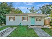 Charming single-story home with light blue exterior, decorative shutters, and a bright turquoise front door at 3714 N Garrison St, Tampa, FL 33619